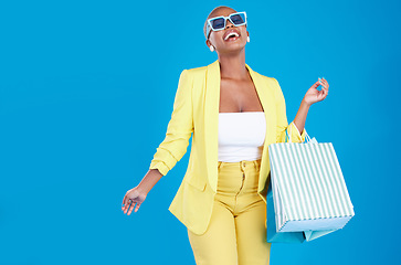 Image showing Fashion, deal and black woman in studio with shopping, bag and glasses, excited and smile on blue background. Retail, store and African female customer happy with boutique, discount and mall sale