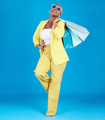 Image showing Fashion, smile and black woman in studio with shopping, bag and glasses or excited for sale on blue background. Retail, store and African female customer happy with boutique, discount and mall deal