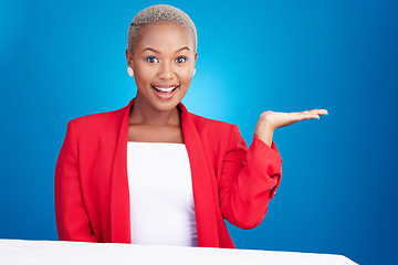 Image showing Portrait, black woman and hand holding in studio for promo, announcement or coming soon deal on blue background. Happy, face and African lady model show mockup, space or prize, giveaway or offer info