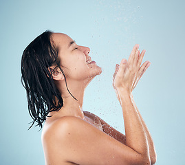 Image showing Skincare, shower and woman smile cleaning in studio isolated on a blue background. Water splash, hygiene and model happy, washing and bathing in wellness, healthy skin beauty of body in bathroom.