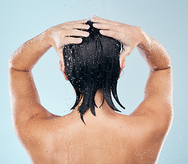 Image showing Hair care, shower and back of woman cleaning in studio isolated on a blue background. Water splash, hygiene and model washing, bathing and cosmetics for wellness, beauty and body health in bathroom