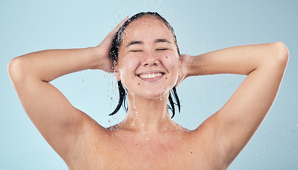 Image showing Shower, water or happy woman cleaning hair or body for wellness in studio on blue background. Smile, beauty or wet female person washing or grooming for healthy natural hygiene or skincare to relax