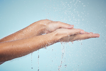 Image showing Cleaning, hands and water splash on woman in studio, blue background and healthcare mockup and washing for skincare. Model, closeup or hygiene with clean, soap or bubbles for protection from bacteria