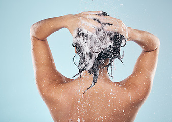 Image showing Hair shampoo, cleaning and back of woman in shower in studio isolated on blue background. Water splash, hygiene and soap, foam or cosmetics of model washing, bath or wellness in body care in bathroom