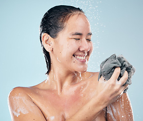 Image showing Woman, shower and clean with water, soap and sponge for healthy dermatology, skincare and blue background in studio. Person, smile and washing skin, body and self care with cosmetics in bathroom