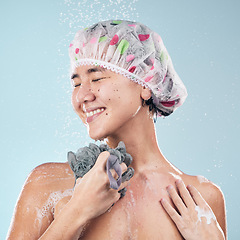 Image showing Happy woman, shower and water drops with loofah in hygiene, grooming or washing against a blue studio background. Female person in relax body wash, cleaning or skincare routine under rain in bathroom