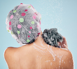 Image showing Person, shower and back in water drops for hygiene, grooming or washing against a blue studio background. Rear view of model in soapy body wash, cleaning or skincare routine under rain in bathroom