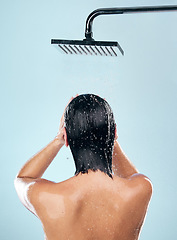 Image showing Woman, shower and back in water drops for hygiene, grooming or washing against a blue studio background. Rear view of female person in body wash, cleaning or skincare routine under rain in bathroom