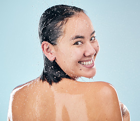 Image showing Skincare, shower back and face of woman cleaning in studio isolated on a blue background. Water splash, hygiene and portrait of happy Asian model washing in bath for wellness, health and body beauty