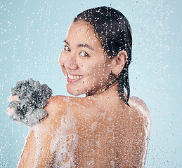 Image showing Woman, portrait and shower with water, soap and sponge for cleaning with dermatology, skincare and blue background in studio. Person, smile and washing skin and body with foam bubbles in bathroom