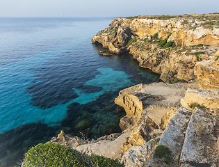 Image showing A landscape with a rocky coast and blue water in the evening.