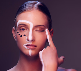 Image showing Woman, skin and paint in studio, wink and closeup for art, wellness or fantasy with cosmetic by dark background. Girl, model and facial painting for eyes, creativity or pattern with makeup for change