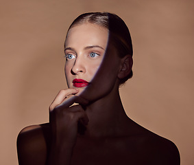 Image showing Spotlight, face and woman with makeup in shadow with dark, beauty and creative aesthetic in studio background. Light, female model and thinking about cosmetics with mystery, art or style in skincare
