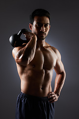 Image showing Training focus, portrait and man with kettlebell workout, muscle building and fitness results, motivation or weightlifting. Gym equipment, bodybuilder focus and dark studio athlete on grey background