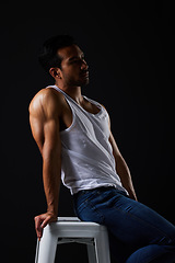 Image showing Sexy, thinking and man on chair in studio with fitness inspiration, strong aesthetic and fashion. Art, body and healthy male model sitting on black background, bodybuilder muscle in dark lighting.