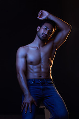 Image showing Bodybuilder man, abs and dark in studio portrait, jeans or muscle for healthy body by black background. Young guy, fitness and silhouette with face, stomach or strong for health, shirtless or fashion