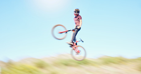 Image showing Blur, air and cyclist cycling in nature training for a competition on trail or path in forest or woods. Freedom, wheelie stunt or athlete riding bicycle to jump in cardio exercise, fitness or workout