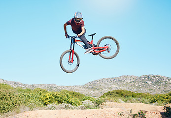 Image showing Freedom, air and man cycling in nature training for a sports competition on trail or path on mountain. Action, stunt or cyclist athlete riding bicycle to jump for cardio exercise, fitness or workout