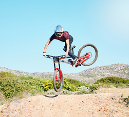 Image showing Action, air and man cycling in nature training for a sports competition on trail or path on mountain. Freedom, stunt or cyclist athlete riding bicycle to jump for cardio exercise, fitness or workout