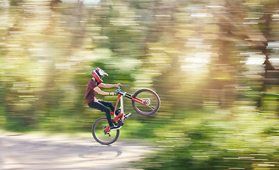 Image showing Blur, air and man cycling in nature training for a competition on trail or path in forest or woods. Freedom, stunt or cyclist athlete riding bicycle to jump for cardio exercise, fitness or workout