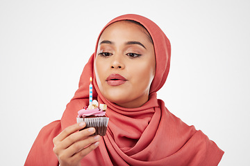 Image showing Muslim, woman and cupcake with candle, birthday wish and celebration with dessert isolated on white background. Blowing flame, cake and sweets, hijab and party with event, food and gift in studio