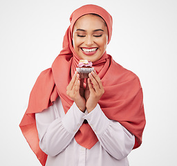 Image showing Smile, cupcake and celebration with a muslim woman in studio on a white background for dessert. Face, food and a happy young islamic person eating a cake, candy or sugar snack at a party event