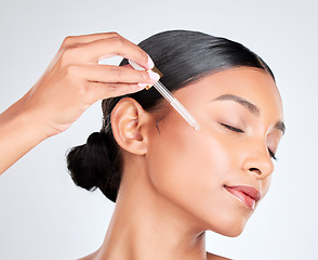 Image showing Face, woman and pipette with cosmetics, oil and serum with wellness on white studio background. Person, skincare product or model with hyaluronic acid, aesthetic or shine with dermatology or beauty