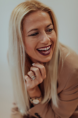 Image showing A confident and successful businesswoman, with a wide smile, strikes a pose in front of a beige background, exuding professionalism and elegance