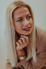 Image showing A confident and successful businesswoman, with a wide smile, strikes a pose in front of a beige background, exuding professionalism and elegance