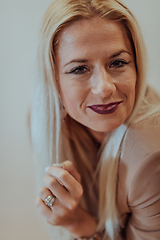 Image showing A confident and successful businesswoman, with a wide smile, strikes a pose in front of a beige background, exuding professionalism and elegance