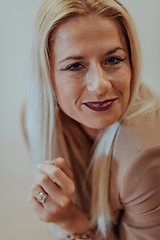 Image showing A confident and successful businesswoman, with a wide smile, strikes a pose in front of a beige background, exuding professionalism and elegance