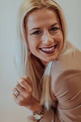 Image showing A confident and successful businesswoman, with a wide smile, strikes a pose in front of a beige background, exuding professionalism and elegance