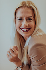 Image showing A confident and successful businesswoman, with a wide smile, strikes a pose in front of a beige background, exuding professionalism and elegance