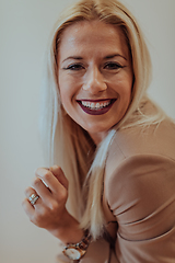 Image showing A confident and successful businesswoman, with a wide smile, strikes a pose in front of a beige background, exuding professionalism and elegance