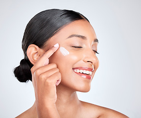 Image showing Smile, cream and woman with beauty, cosmetics or apply lotion on a white studio background. Person, happy and model with creme, moisturiser and shine with self care, beauty and aesthetic with glow