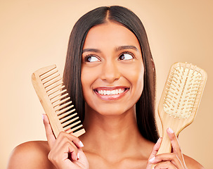 Image showing Brush, comb and young woman in a studio for salon, keratin or cosmetic treatment for wellness. Health, happy and Indian female model with natural bamboo hair tools isolated by a brown background.