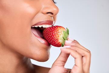 Image showing Health, closeup and woman eating strawberry in a studio for healthy diet snack for nutrition. Wellness, beauty and zoom of female model with fruit for natural skin detox routine by a gray background.