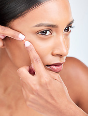 Image showing Face, woman and squeeze acne in studio of glowing spot, breakout or check dermatology on white background. Indian model, facial beauty and pop pimple, scratch blackhead and scar of sensitive skincare