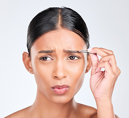 Image showing Beauty, pain and woman with tweezers for eyebrow in studio, tools for self care and grooming. Facial hair removal, dermatology and eye skincare, face of model on white background for clean skin glow.