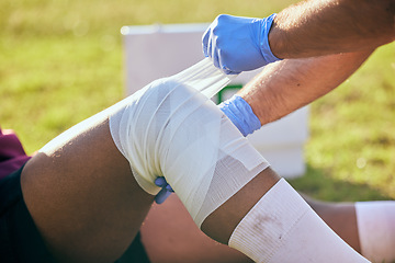 Image showing First aid, sport injury and leg bandage with soccer accident, fitness and massage on a field. Training, workout and physical therapy of knee pain at game with healthcare emergency from exercise