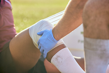 Image showing First aid, sport injury bandage and hands on knee with soccer accident, fitness and massage on a field. Training, workout and physical therapy of leg pain at game with emergency from exercise