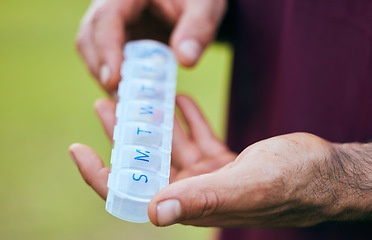 Image showing Pill box, weekly medicine and hand closeup of a sport athlete on a soccer field with tablet and drugs for health. Supplements, plastic container and outdoor with a man holding wellness and medication