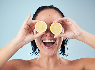 Image showing Eyes, smile or happy woman with lemon for skincare or beauty in studio on blue background. Crazy, dermatology shine or funny person with natural fruits, vitamin c or face glow for wellness or health