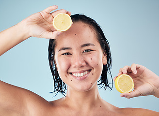 Image showing Portrait, smile or happy woman with lemon for skincare or beauty in studio on blue background. Dermatology, shine or Asian person with natural fruits, vitamin c or face glow for wellness or health