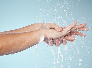 Image showing Woman, cleaning and hands with water splash in studio, blue background and healthcare mockup or washing in skincare. Model, closeup or hygiene with clean, soap or bubbles for protection from bacteria