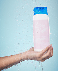 Image showing Person, hand and shower gel with product in hygiene, washing or cleanse against a blue studio background. Closeup of model holding skin cosmetics, soap or body care with water drops in bathroom