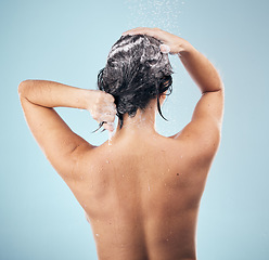Image showing Hair shampoo, shower and back of woman cleaning in studio isolated on a blue background. Water splash, hygiene and soap, foam or cosmetics of model washing, bath or wellness for body care in bathroom
