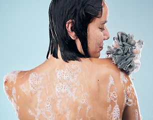 Image showing Woman, back and cleaning body with water, soap and sponge for dermatology, skincare and blue background in studio. Healthy, person and washing skin with self care, cosmetics or peace in bathroom