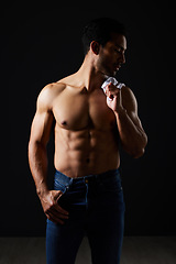 Image showing Sexy, muscle and topless man on black background with fitness inspiration, strong aesthetic and fashion. Art, body motivation and muscular male model in studio, thinking in dark lighting and jeans.