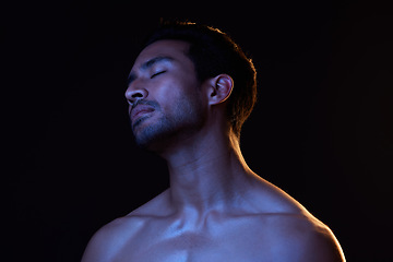 Image showing Blue light, relax man and sleep with creative, art and dark background in studio. Sexy, eyes closed and male model from Indonesia with skin glow, grooming care and wellness for skincare treatment